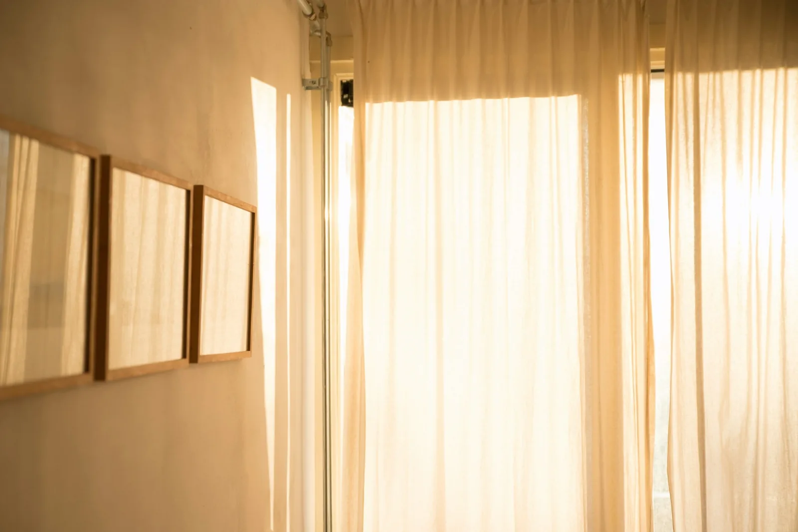 Una habitación clara con cortinas de lino y la luz de la mañana atravesándolas.